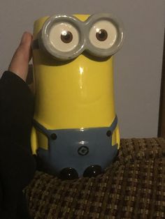 a person holding up a yellow and blue toy with googly eyes on it's face