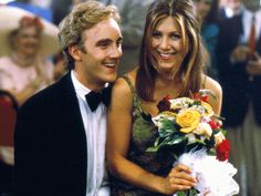 a man in a tuxedo holding a bouquet of flowers next to a woman