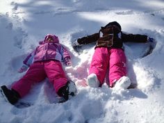 two children are laying in the snow together