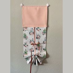 a pink and white tie hanging from the side of a wall with flowers on it