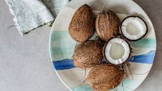 some coconuts are on a plate and one is cut in half