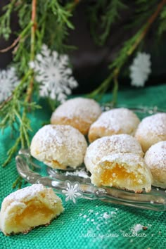 powdered sugar covered pastries on a glass platter next to snowflakes