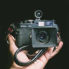 a person holding an old camera in their hand with the lens attached to it's body