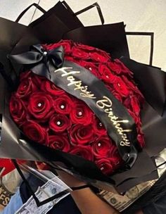 a large bouquet of red roses wrapped in black paper