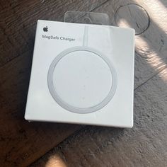 an apple charger sitting on top of a wooden floor next to a box with the packaging