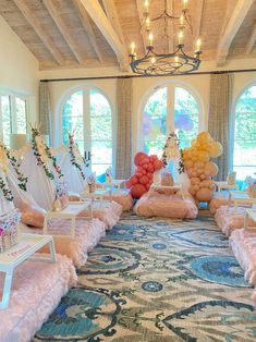 a large room filled with lots of balloons and tables covered in pink fluffy materials