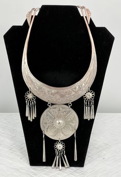 "Vintage Thailand Collar Necklace/Etched Floral/Silver Platted/12\" L x 5 1/2\". Stunning Vintage Hmong Miao Torque silver necklace . Silver plate brass ceremonial Torque Necklace with fringe & bells. Hand engraved with botanical scroll motif & elongated links. Hangs and moves beautifully, the bib fits with hook closure. Good vintage condition, the few areas that are showing age are some of the silver around the neck area is faded and the two top dangling flowers are pushed in. Please see pictures for full details. Miao silver is not pure silver, but an alloy of silver, copper and nickel. It's a traditional material for making jewelry by craftsmen of Miao Hmong ethnic tribe. Necklace hangs: 12\" long x 5 1/2\" wide" Artisan Silver Etched Necklace, Ceremonial Silver Medallion Necklace, Silver Medallion Necklace For Ceremonial, Silver Medallion Necklace For Ceremonial Occasions, Ceremonial Silver Jewelry With Large Pendant, Silver Jewelry With Large Pendant For Ceremonial Occasions, Ceremonial Silver Medallion Jewelry, Bohemian Etched Silver Necklace, Traditional Etched Antique Silver Necklace