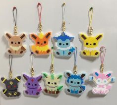 six pixelated pokemon key chains hanging on a white wall, each with different colors and sizes