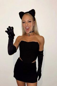 a woman dressed up as a cat with her hands in the air and wearing black gloves