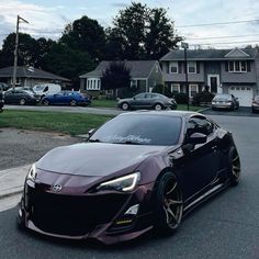 a purple sports car parked on the side of a road in front of some houses