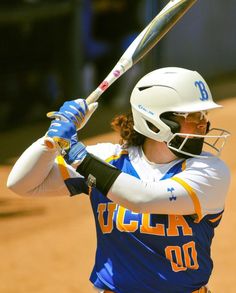 a woman holding a baseball bat on top of a field