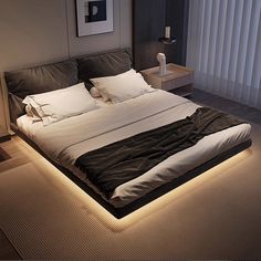 a large bed with white sheets and pillows in a room that is lit up at night