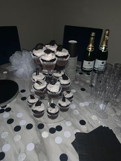 a table topped with cupcakes and champagne glasses next to bottles of wine on top of a polka dot covered table cloth