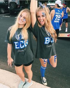 two girls with face paint are standing in the street and one is holding her arm up