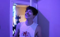 a young man standing in front of a purple wall and looking up at the ceiling