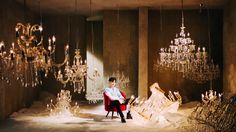 a man sitting in a chair surrounded by chandeliers