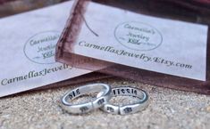 two wedding rings sitting on the ground next to each other with their names printed on them