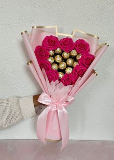 a bouquet of pink roses with chocolates in the shape of a heart