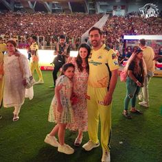 two women and a man are standing in front of a crowd at a cricket game