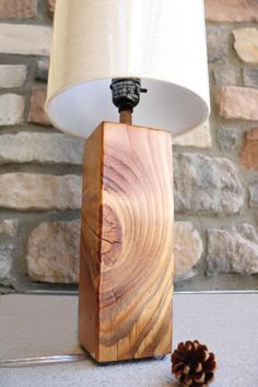 a table lamp made out of wood with a pine cone on the side and a white shade