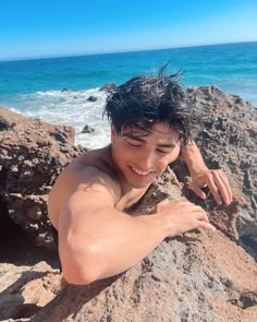 a man laying on top of a rock next to the ocean