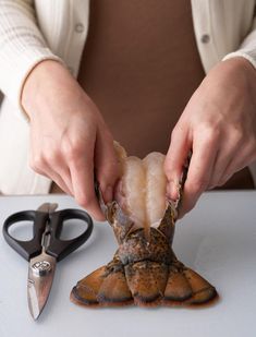 a person cutting up some food on top of a white table next to scissors and a pair of shears