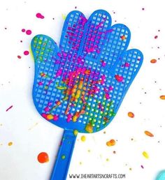 a blue plastic spatula with colored sprinkles on it and a hand shaped like a glove