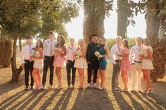 a group of people standing next to each other in front of some palm trees on a sunny day