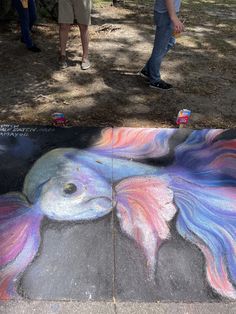 two people standing next to a chalk drawing of a woman's face and fish