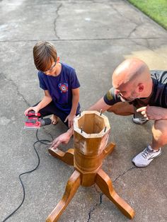 a man and boy are working on a wooden object