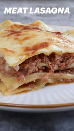 a white plate topped with lasagna covered in meat and cheese on top of it