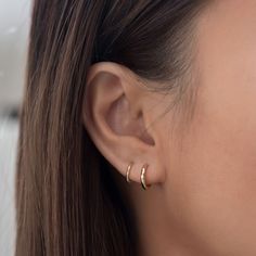 a close up view of a woman's ear with two small rings on it