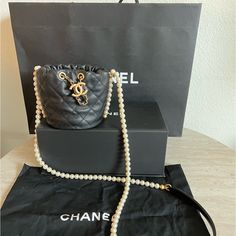 New In The Box This Is An Authentic Chanel Calfskin Quilted Pearl Mini About Pearls Drawstring Bucket Bag In Black. This Crossbody Bag Features A Resin Pearl Shoulder Strap With A Black Leather Shoulder Pad And A Leather Threaded Aged Gold Chain Drawstring. This Opens To A Red Fabric Interior. Base Length: 4.25 In Height: 4.5 In Width: 4.5 In Drop: 23 In Receipt Upon Requested Resin Pearl, Mini Bucket Bag, Chanel Pearls, Mini Bucket Bags, Mini Bucket, Drawstring Bucket Bag, Leather Thread, Red Fabric, Shoulder Pads