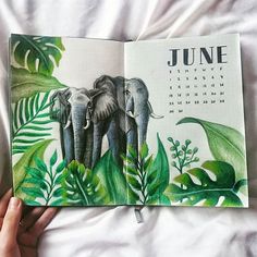 someone is holding an open calendar with two elephants in the jungle on it's cover