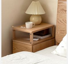 a nightstand with a lamp on top of it next to a bed