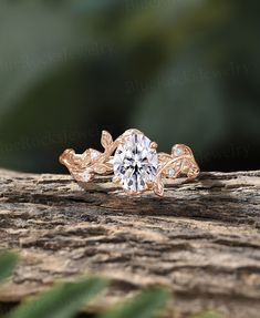 an engagement ring on top of a piece of wood with leaves and diamonds in the center