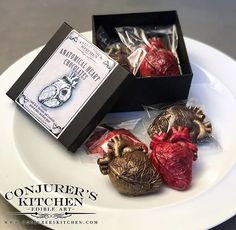 three heart shaped candies on a plate with an empty box in the middle, and one wrapped in cellophane