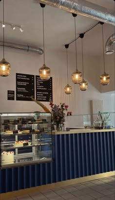 the inside of a bakery with lights hanging from the ceiling