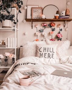 a bed with white sheets, pillows and pink flowers on the headboard next to a laptop