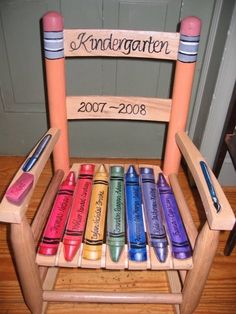 a child's wooden rocking chair with crayons on the seat and name written on it