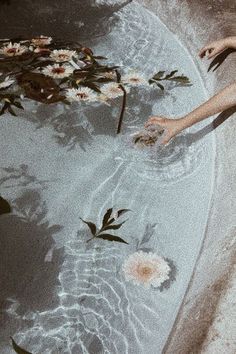 a person reaching for some flowers in the water with their hands and feet above them