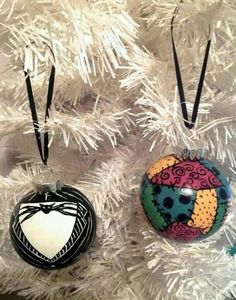 three ornaments are hanging from a white christmas tree, one is decorated with an ornament and the other has a heart on it