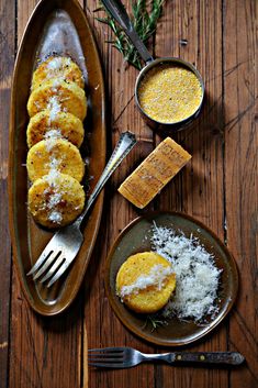 some food is laying out on a wooden table next to two plates with silverware