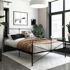 a bed sitting in a bedroom next to a window with plants on the side of it