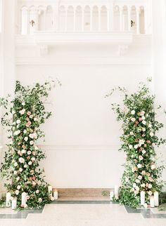 an indoor ceremony with candles and greenery on the floor, surrounded by white walls