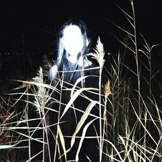 a woman standing in tall grass at night