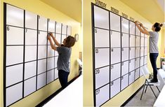 a woman standing on top of a giant white board next to a wall with calendars