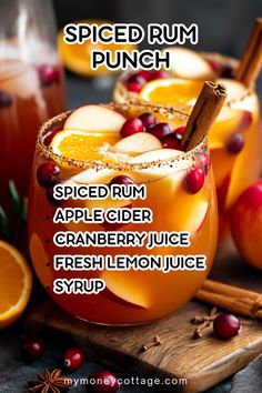 two glasses filled with spiced rum punch and garnished with cinnamon, apple cider, cranberry juice and fresh lemon juice