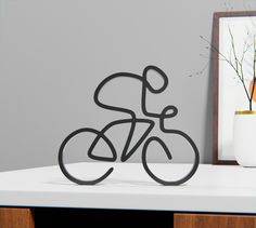 a metal bike sculpture sitting on top of a white table next to a framed photo