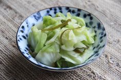 a bowl filled with lettuce sitting on top of a table next to a cloth